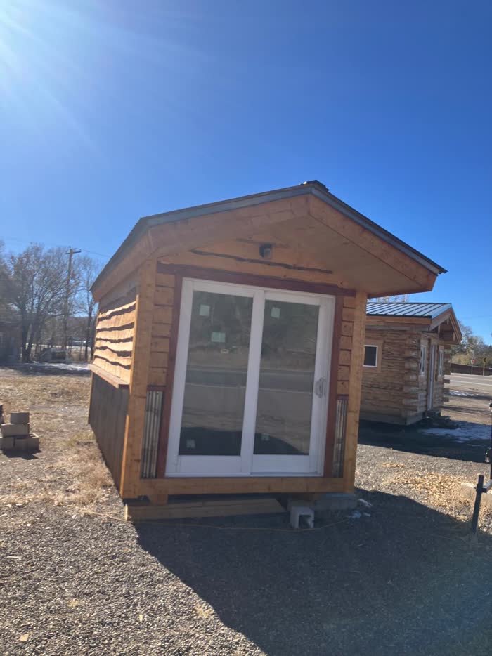 Small wooden cabin with live-edge siding and a sliding glass door